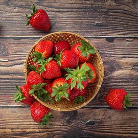 Fresh strawberries in a bowl on wooden table