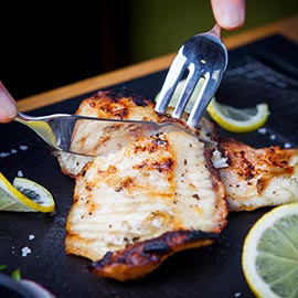 Side view fried fish with knife and fork on dark background